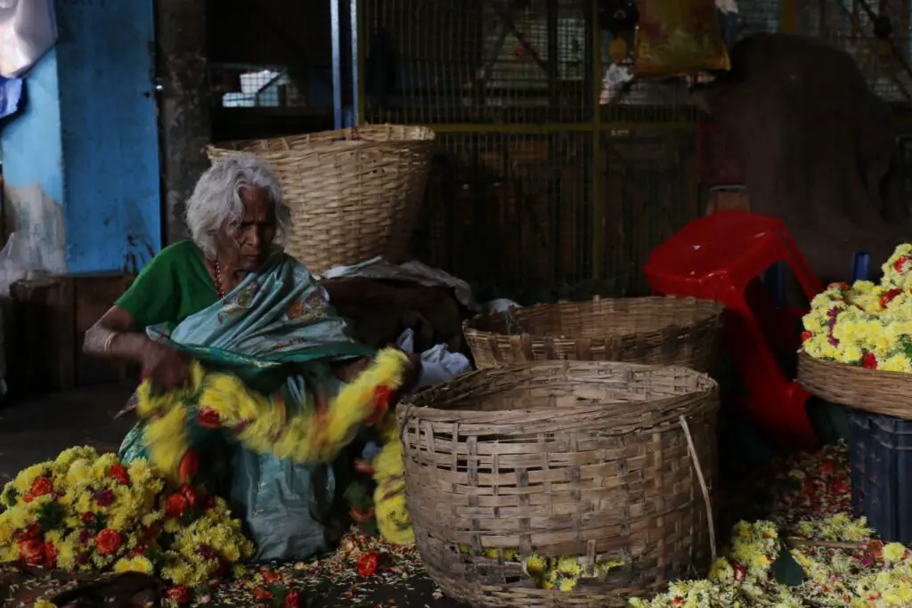 Old woman collecting flowers in Bangalore market
